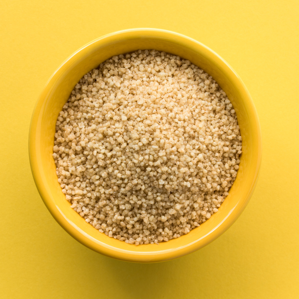 Skåle med gylden bulgur i forskellige grovheder og forskellige typer af pasta på en rustik baggrund.
