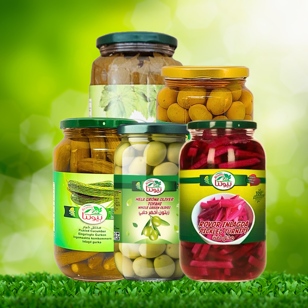 Glas med forskellige farverige syltede delikatesser, pickles og chutneys opstillet på et køkkenbord.